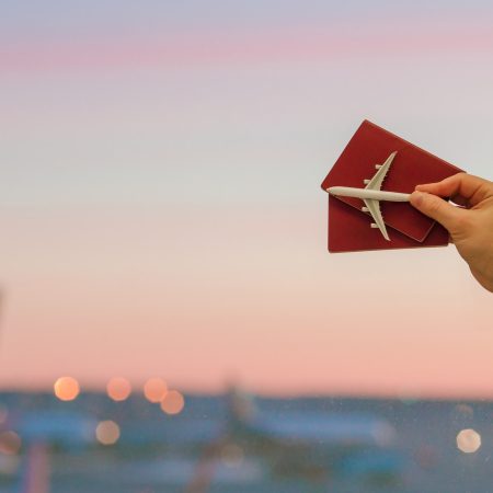 closeup-an-airplane-model-toy-and-passports-at-the-airport-background-big-window-at-dawn-1